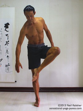 Sensational Yoga Poses, Model Neil Keleher. balancing on one leg while moving into eagle pose with lifted foot in front of the standing leg knee.