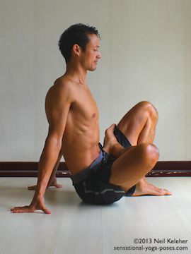 one foot in marichyasana other foot in lotus with hands on floor behind buttocks as a preparation for marichyasana b
