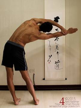 moon pose, chandrasana, standing side bend with feet hip width and arms overhead. Hand of top arm is grabbing wrist of bottom arm with bottom elbow straight