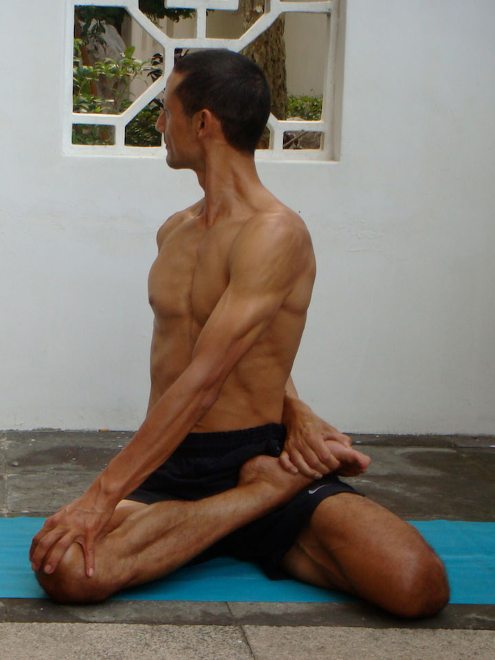 baradvajrasana, sage pose, front view with hand on knee
