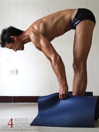 Standing forward bend grabbing on to sides of a yoga mat. Neil Keleher. Sensational Yoga Poses.