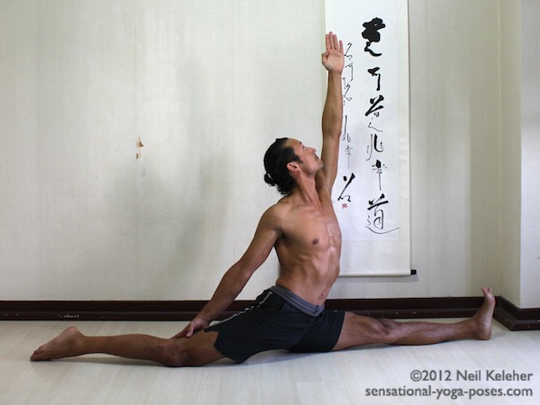 In this back bending front to back splits the upper body is upright. Both knees are straight with the back knee pointing down. The back leg arm is reaching towards the back knee. The front leg arm is reaching upwards.