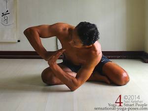 easy bharadvajasana bending forwards and twisting the spine with hands in prayer in front of ribcage and elbow supporting ribcage.