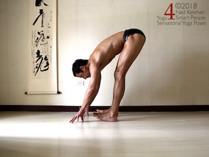 Standing forward bend balancing on heels with hands touching the floor. Neil Keleher. Sensational Yoga Poses.