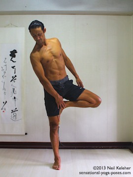 Sensational Yoga Poses, Model Neil Keleher. balancing on one leg while moving into tree pose by bending towards the side and grabbing the lifted foot with the opposite hand and placing it agains the inner thigh