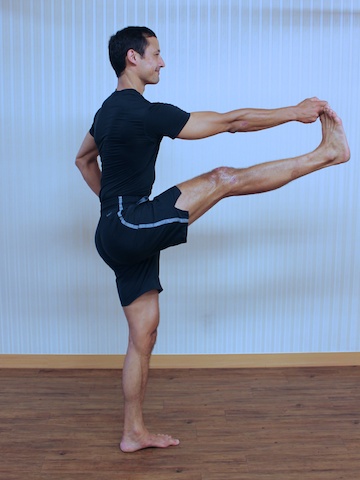 Full length portrait of young fit woman doing a yoga pose standing with one  leg raised up. Utthita Hasta Padangusthasana Stock Photo